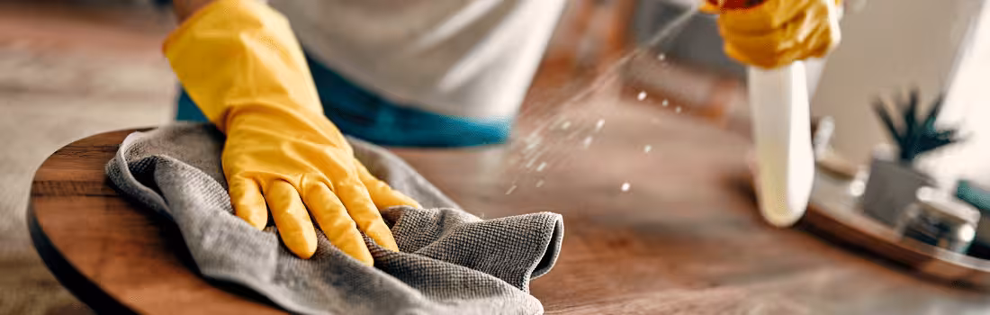 A person wiping down a counter to avoid making cleaning mistakes