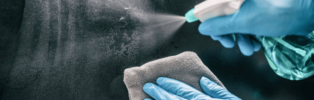 A person wiping down a surface with antibacterial spray
