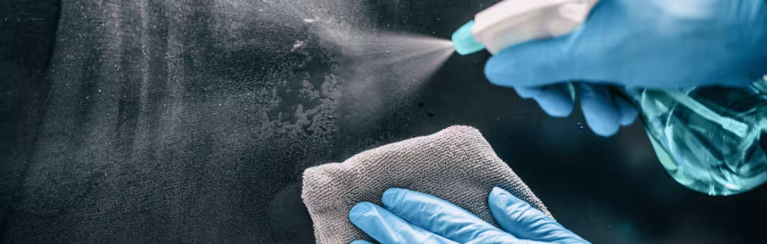 A person wiping down a surface with antibacterial spray